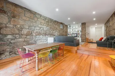 a living room with a stone wall and a table and chairs at GuestReady - Breyner Stonewall Haven in Porto