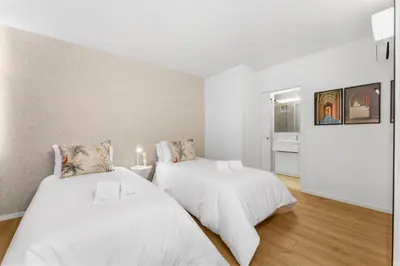 two beds in a room with white walls and wood floors at Sittium in Porto