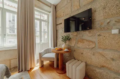 a room with a table and a tv on a stone wall at Clerigos Boutique Apartments by Hosty in Porto