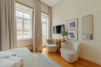a bedroom with a bed and a table and a chair at Clerigos Boutique Apartments by Hosty in Porto