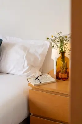 a bed with a table with a book and a vase with flowers at Porto 61 - Bright 2BR w/ Balcony by LovelyStay in Porto