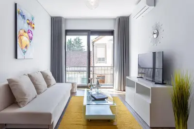 a living room with a white couch and a tv at Urban Views - ML Apart Inspired by Palácio de Cristal in Porto