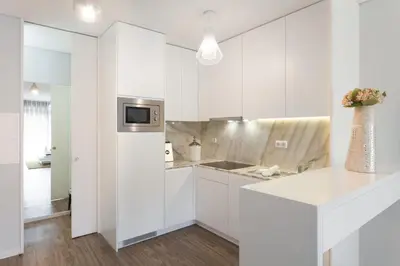 a white kitchen with white cabinets and a counter at Urban Views - ML Apart Inspired by Palácio de Cristal in Porto