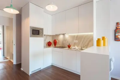 a white kitchen with white cabinets and red vases at Urban Views - ML Apart Inspired in Serralves in Porto