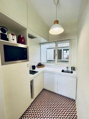a small kitchen with white cabinets and a window at Stylish Flat City Center in Porto