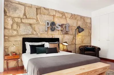 a bedroom with a large bed and a stone wall at Oporto Chic & Cozy Studio Apartments in Porto