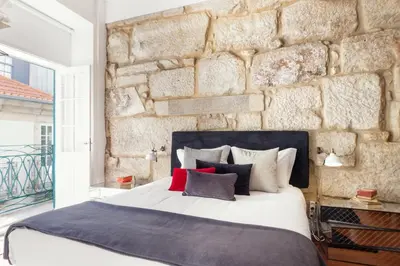 a bedroom with a stone wall and a bed with pillows at Oporto Chic & Cozy Studio Apartments in Porto