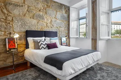 a bedroom with a large bed and a stone wall at Oporto Chic & Cozy Studio Apartments in Porto