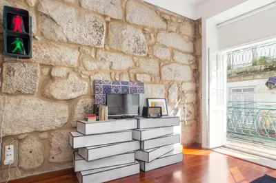 a living room with a tv and a stone wall at Oporto Chic & Cozy Studio Apartments in Porto
