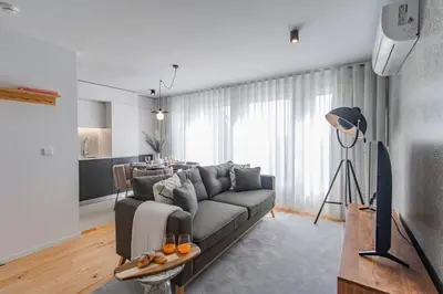 a living room with a gray couch and a kitchen at João das Regras 321 by LovelyStay in Porto