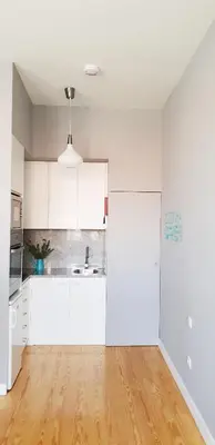 an empty kitchen with white cabinets and a wooden floor at Toctoc Studio in Porto