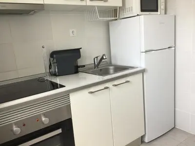 a white kitchen with a sink and a refrigerator at Vicky Porto in Porto