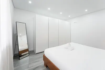a white bedroom with a bed and a mirror at GuestReady - Casegas residence in Marquês in Porto