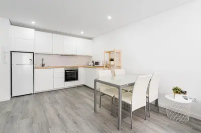 a kitchen with white cabinets and a table and chairs at GuestReady - Casegas residence in Marquês in Porto