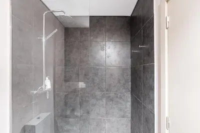 a bathroom with a shower with a glass door at GuestReady - Quental Wallpaper near Marquês Square in Porto