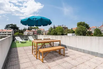 a table and a bench and an umbrella on a roof at GuestReady - Portrait with a view in Porto