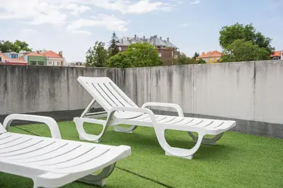 three white chairs sitting on the grass on a roof at GuestReady - Portrait with a view in Porto