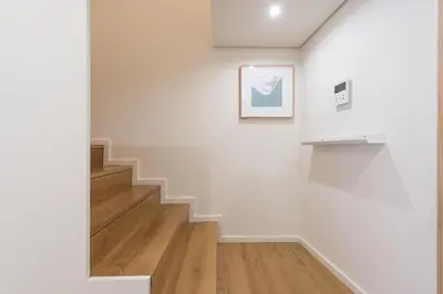 a staircase in a white room with a picture on the wall at AgapeStay Family House in Porto