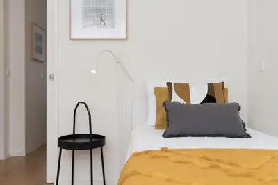 a bedroom with a bed with yellow sheets and a black stool at AgapeStay Family House in Porto