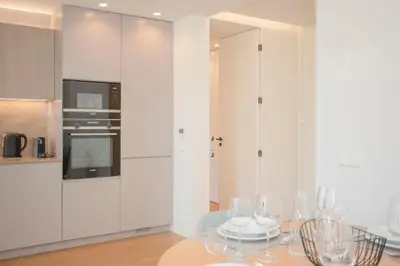 a kitchen with white cabinets and a table with wine glasses at Liiiving in Porto - Crystal Palace Apartment in Porto