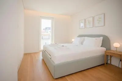 a white bedroom with a large bed and a window at Liiiving in Porto - Crystal Palace Apartment in Porto