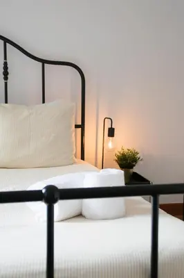 a bed with white sheets and a lamp on a table at Goodgarden Downtown Apartment in Porto