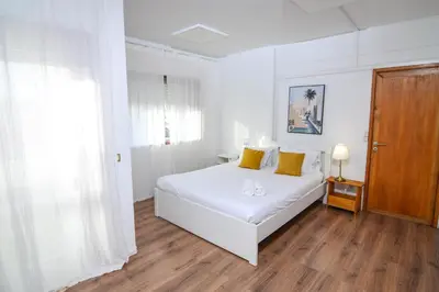 a white bedroom with a white bed and a wooden floor at Travel & Live Fernão Magalhães in Porto