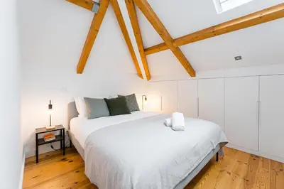two beds in a bedroom with white walls and wooden floors at GuestReady - Freixo Paradise view in Porto