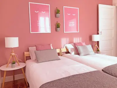 two beds in a room with pink walls at Cozy 3 room apartment near House of Music in Porto
