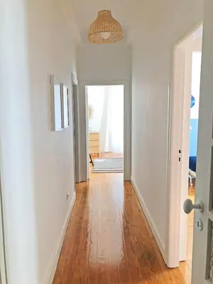 a hallway with white walls and wood floors and a chandelier at Cozy 3 room apartment near House of Music in Porto