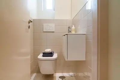 a white bathroom with a toilet and a sink at Charmant appartement climatisé avec balcons in Porto