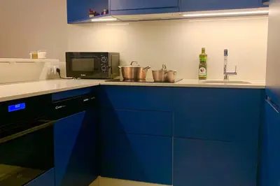 a kitchen with blue cabinets and a microwave at Charmant appartement climatisé avec balcons in Porto