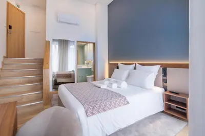 a bedroom with a white bed and a staircase at Alliança Suites 1909 - Porto in Porto