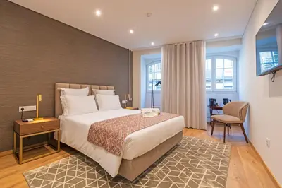 a hotel room with a bed and a chair at Alliança Suites 1909 - Porto in Porto