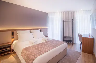 a hotel room with a large bed and a desk at Alliança Suites 1909 - Porto in Porto
