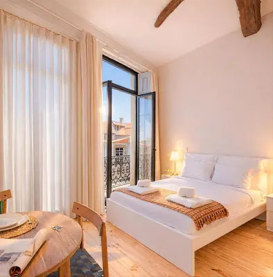 a white bedroom with a bed and a table at FindMe InPorto Bonfim in Porto
