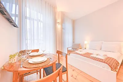 a white bedroom with a bed and a desk and windows at FindMe InPorto Bonfim in Porto