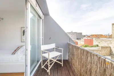 a white chair sitting on a balcony with a window at Design Poveiros Duplex in Porto