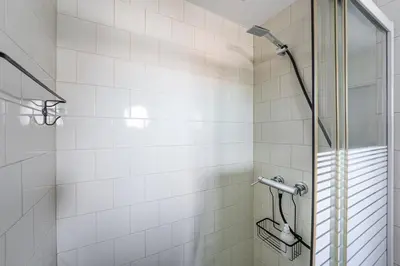 a bathroom with a shower with white tiles at GuestReady - Beer Garden in Porto