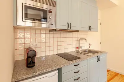 a kitchen with white cabinets and a sink and a microwave at Dasi House in Porto