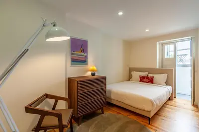 a bedroom with a bed and a lamp and a chair at Dasi House in Porto