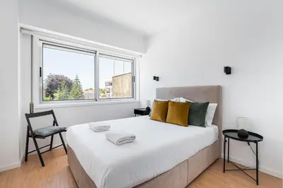 a white bedroom with a large bed and a window at GuestReady - Casa da Música Cosmopolitan Comfort in Porto