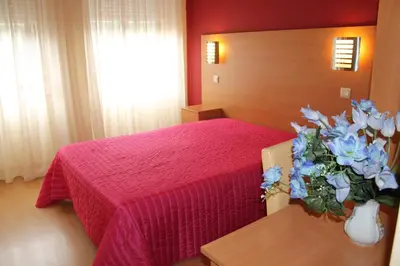 a bedroom with a bed with a red bedspread and flowers at Guest House Estrela in Porto