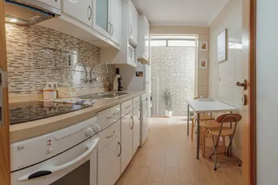 a kitchen with white cabinets and a table in it at Bright Apartment by Hosty in Porto