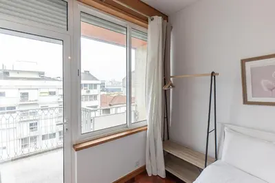 a bedroom with a bed and a large window at Lolla's City House 2 in Porto