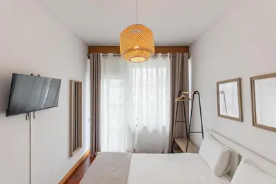 a bedroom with a bed and a tv and a window at Lolla's City House 2 in Porto