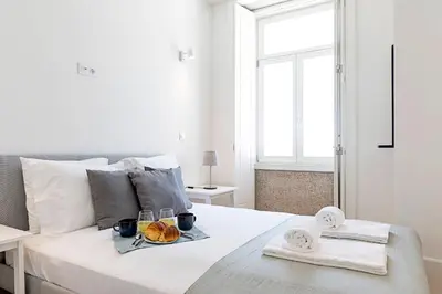 a white bedroom with a bed with a tray of food on it at Cozy and Homely Getaway by LovelyStay in Porto
