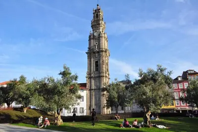 a building with a clock tower with people sitting in the grass at The Flat in Porto