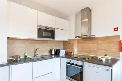 a white kitchen with a sink and a microwave at Lusi'Apartment - Douro River so close by Guest SPA in Porto
