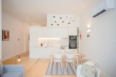 a white kitchen with a table and chairs at Liiiving in Porto - Haven Pool Apartment in Porto